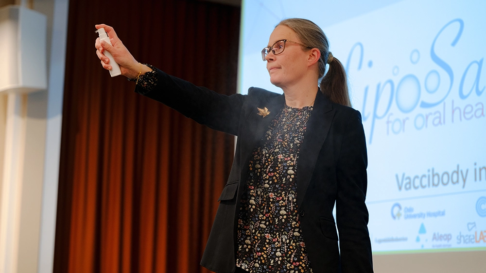 Marianne Hiorth holding the oral spray Liposal in her hand.